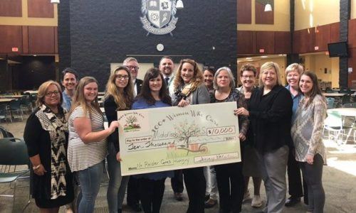 100 Women Who Care holding up a check at Middlebury Schools