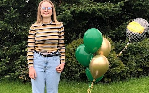 Girl standing in yard with balloons